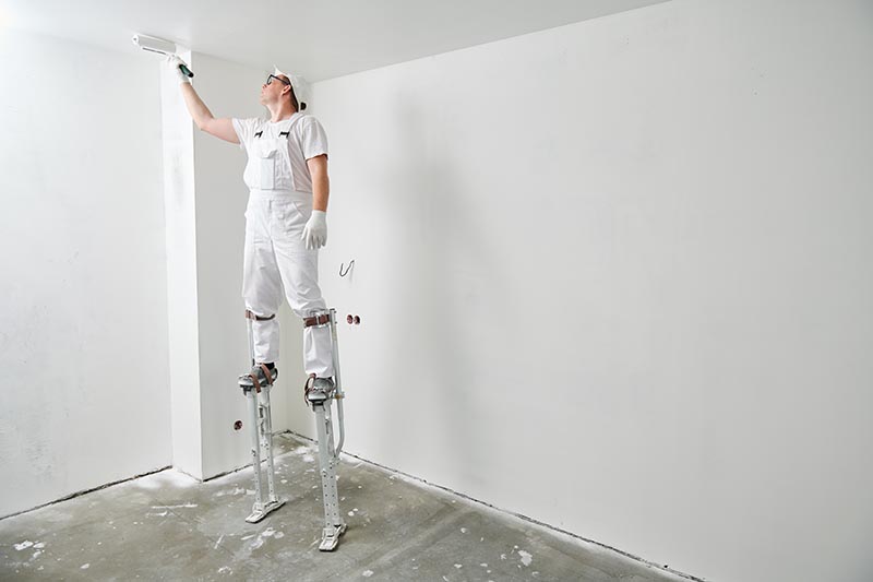 man painting drywall with smooth white