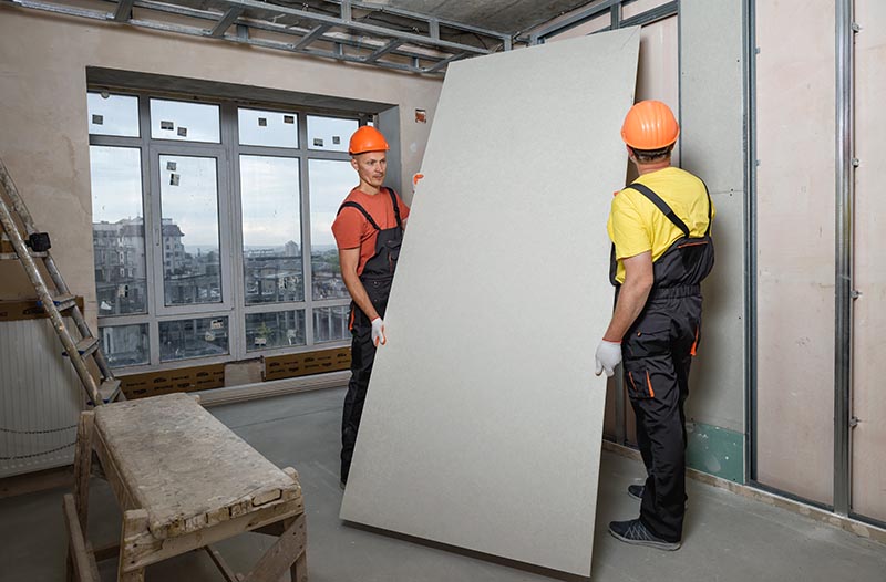 two men installing drywall on the wall