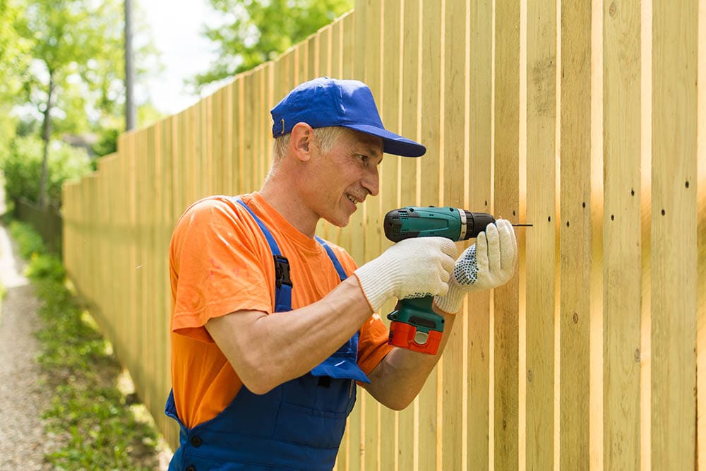 handyman installing wooden fence