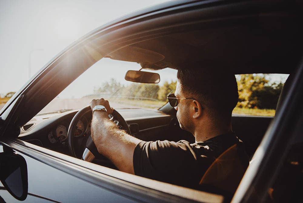 man driving car during sunset