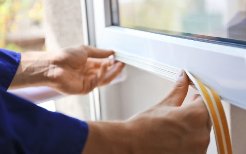 person putting weatherstripping seal on a window