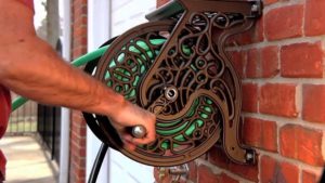 man using Liberty Garden 704 Wall Mount Garden Hose Reel