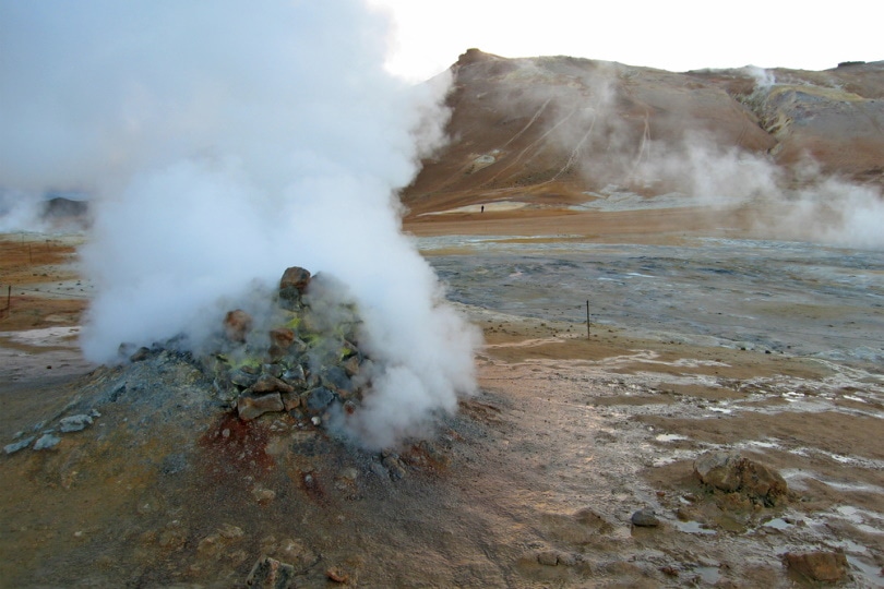 erupting geyser of steam with sulfur deposits