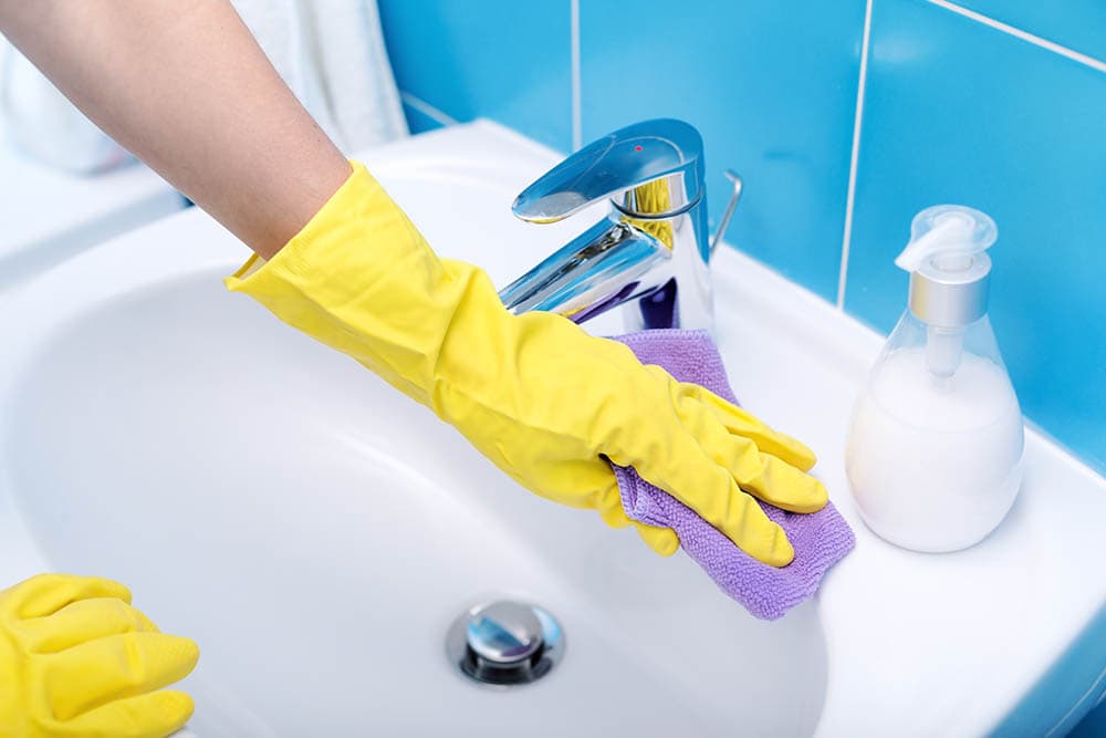 person cleaning the bathroom sink