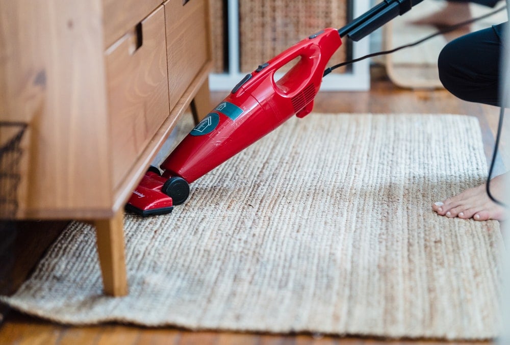 person vacuuming under a cabinet