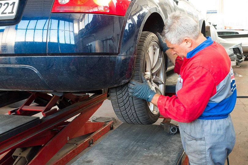 a mechanic checking the tire of a car