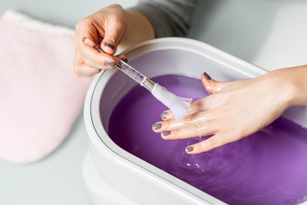 Lilac paraffin wax procuder in hands_Kartinkin77_Shutterstock
