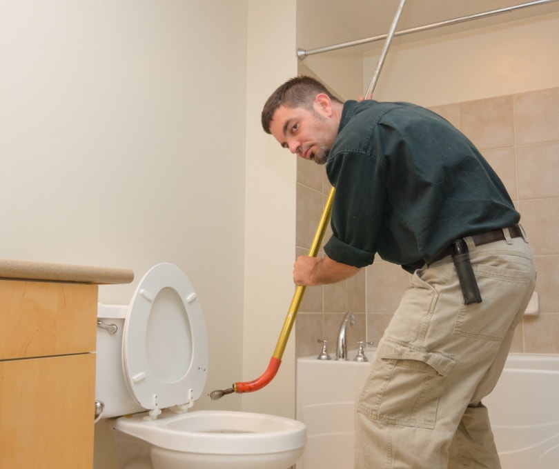 plumber unclogging toilet