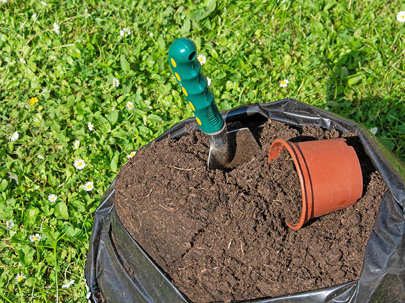 Potting soil in a sack with a shovel and a flower pot