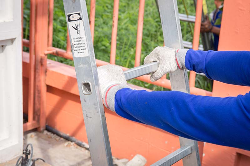 Technician holds the slide ladder with white gloves and blue sleeve