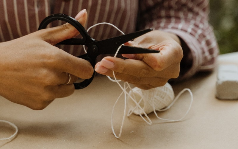 woman cutting a white yarn with scissors